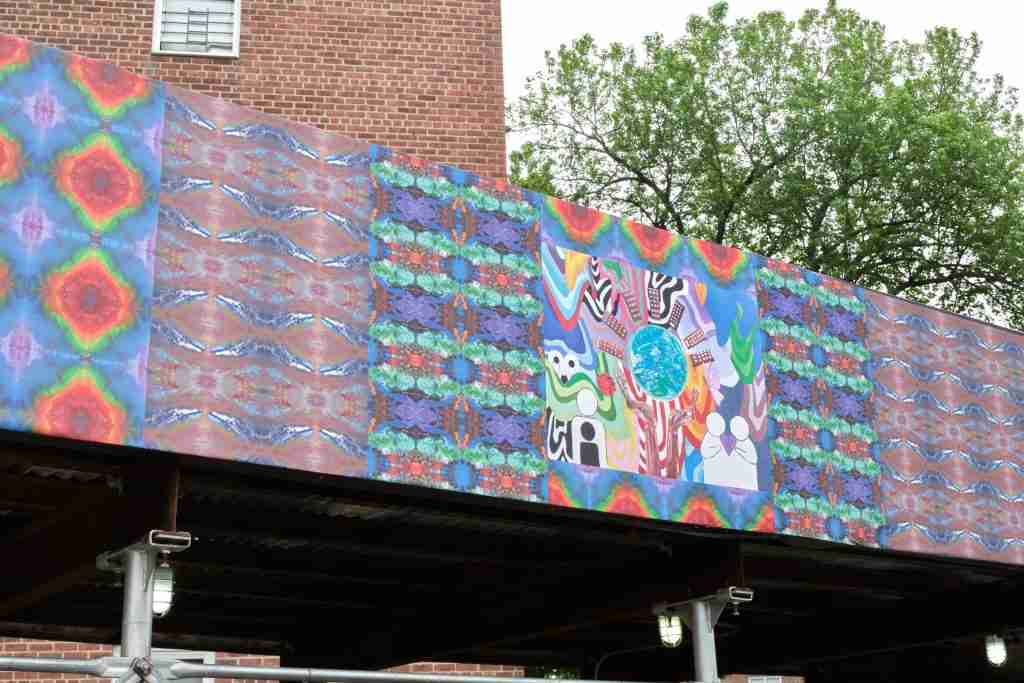 On July 8, a new art exhibition, “Present Power / Future Hopes,” brought outdoor art indoors to showcase the work of 59 New York-based artists who created 25,000 square feet of art to help beautify and bring public art to 17 NYCHA developments across the city. The exhibition is produced by ArtBridge as a culmination of its Bridging the Divide program, a fellowship in which local artists design temporary public artworks that reflect the lives, histories, and aspirations of NYCHA residents. The artists created over 50 new, site-specific artwork that was affixed to construction fencing and sidewalk sheds at each location, as made possible through the NYC Department of Cultural Affairs’ City Canvas pilot initiative. As part of the fellowship, the artists held hundreds of art workshops and community events with NYCHA residents. (See past NYCHA Journal stories on Bridging the Divide here.)